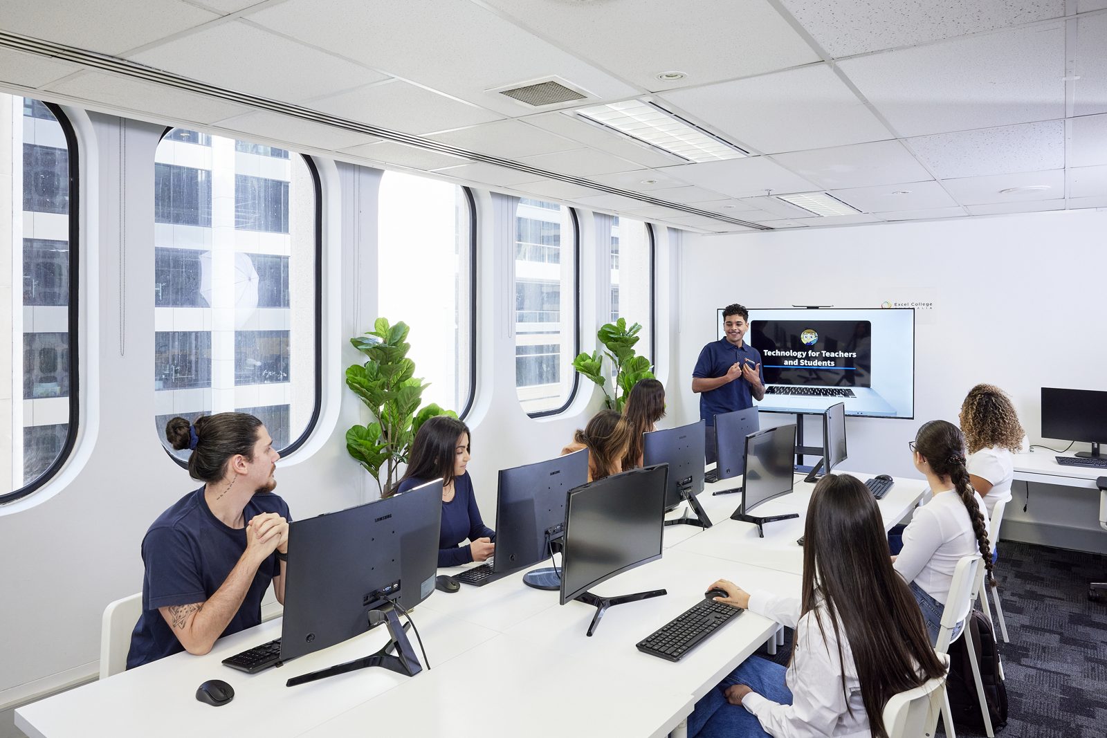 A trainer presenting to students in a modern computer lab