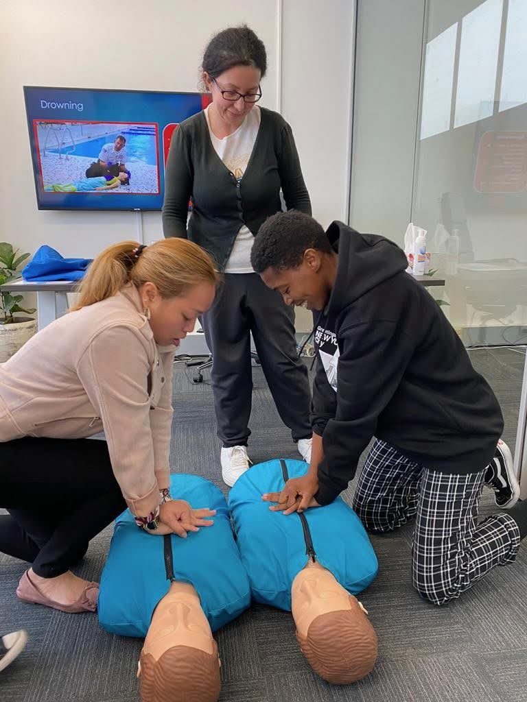 Candidates practising CPR on training manikins under a trainer's supervision