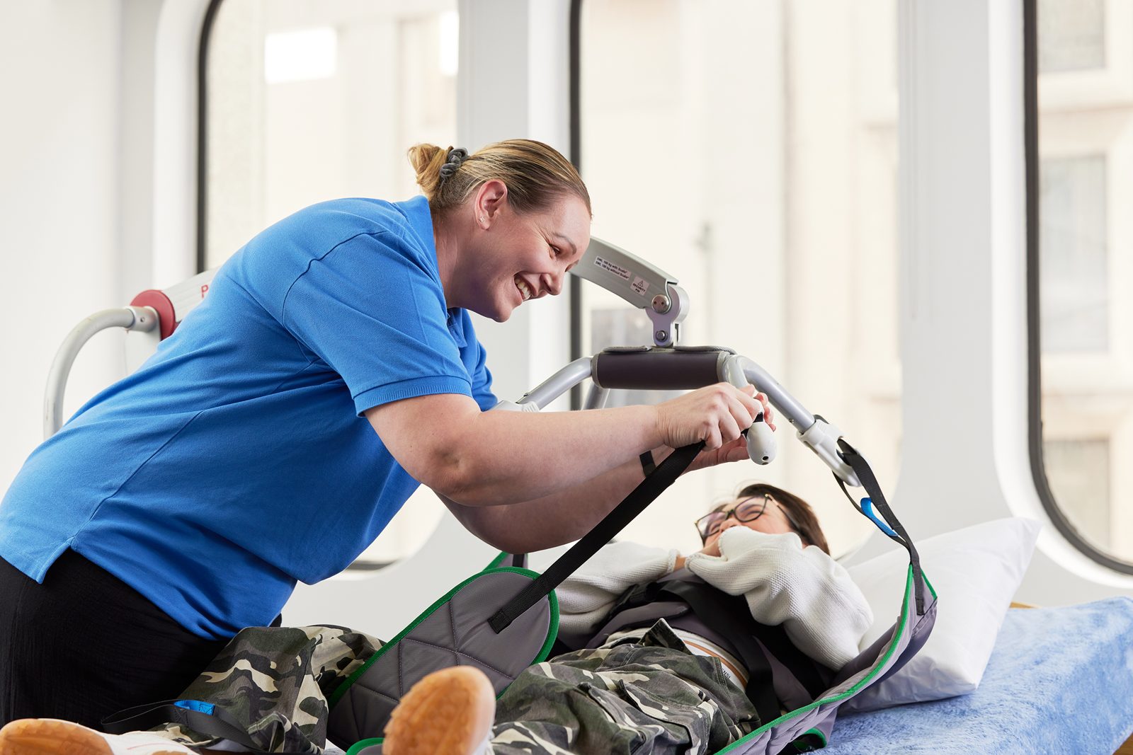 A smiling trainer positioning a hoist sling during a practical Manual Handling session